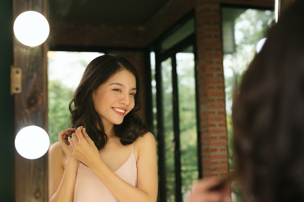 Young woman looking herself reflection in mirror at home