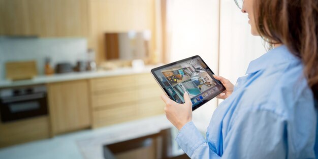 Young woman looking at home security cameras on tablet computer