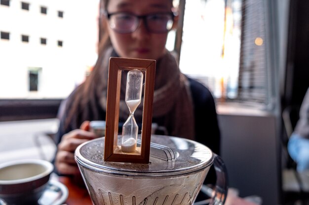 Photo young woman looking at hourglass on container