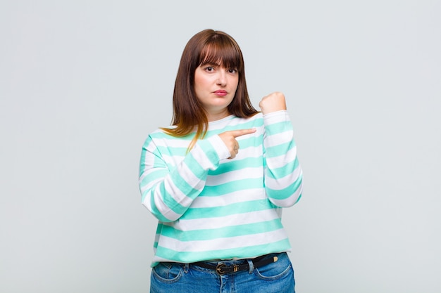 Young woman looking impatient and angry, pointing at watch, asking for punctuality, wants to be on time