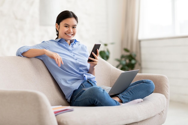 Young woman looking for job online using smartphone and laptop