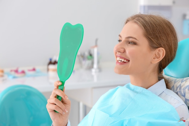 Young woman looking in mirror at dentist's office