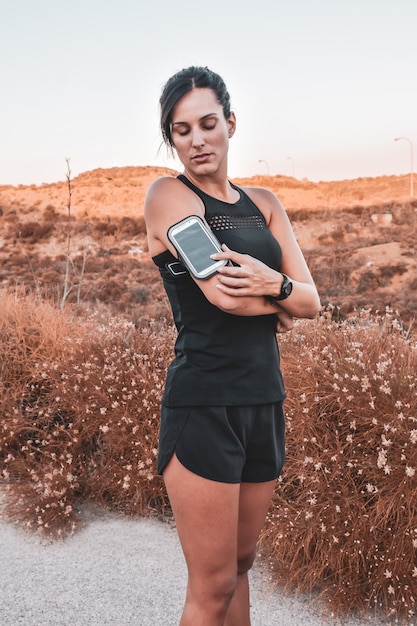 Young woman looking at the mobile phone while running