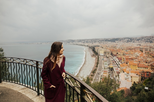 Foto una giovane donna che guarda il bel paesaggio urbano da un punto panoramico su una collina.