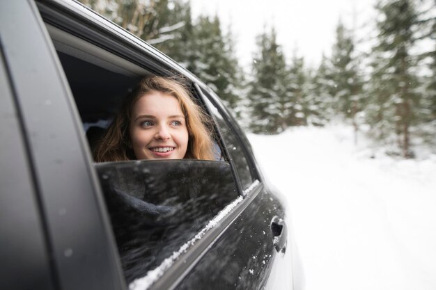 Young woman looking out of a car window in winter landscape