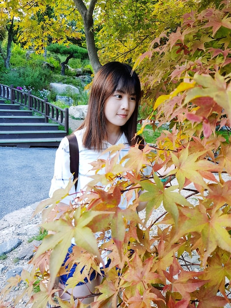 Young woman looking at plants in park during autumn