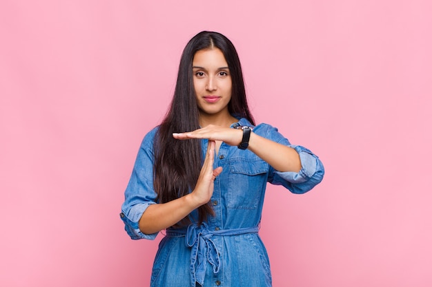 Giovane donna che sembra seria, severa, arrabbiata e scontenta, facendo segno di time out