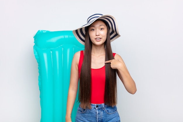 Young woman looking shocked and surprised with mouth wide open, pointing to self