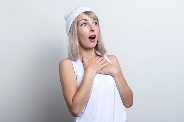 Young woman looking surprised to the side on a light background.