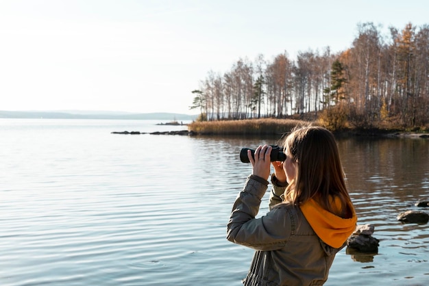 Photo young woman looking through binoculars at birds on lake birdwatching zoology ecology research