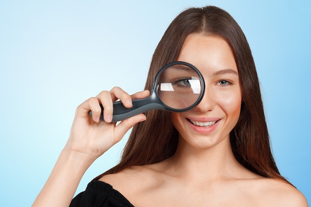 Young woman looking through a magnifying glass