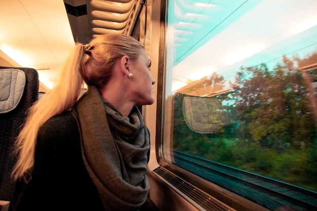 Foto giovane donna che guarda attraverso la finestra mentre viaggia in treno
