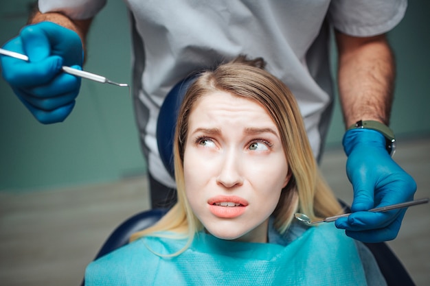 Young woman looking at tools for teeth treatment with fear