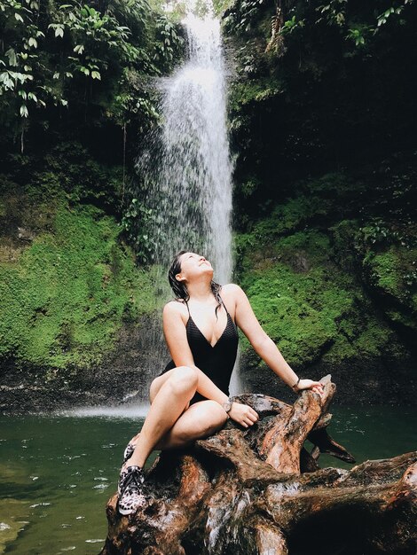 Foto giovane donna che guarda una cascata nella foresta