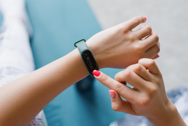 Young woman looks at a sports watch checking performance or heart rate Sports and fitness at home