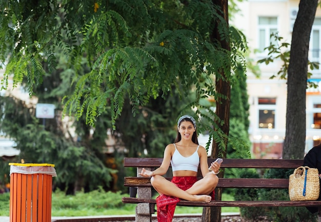 A young woman in the lotus position on a park bench
