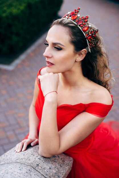 Young woman in a luxurious red dress on the architecture, close-up