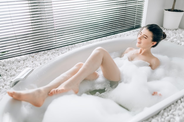 Young woman lying in bath with foam, blured view