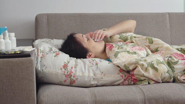young woman lying on the bed with a cough.