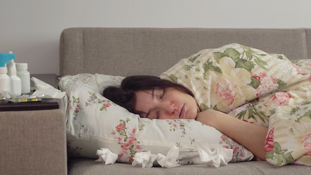 Young woman lying on the bed wrapped in a blanket.