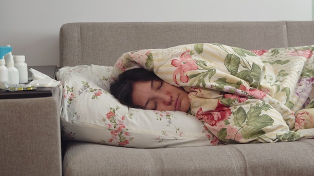 Young woman lying on the bed wrapped in a blanket.