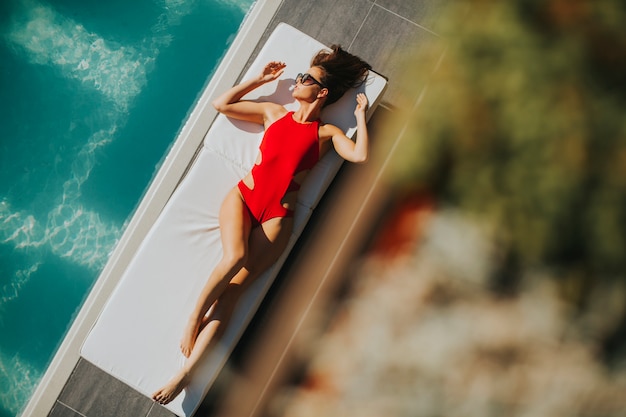 Young woman lying by the pool on bed