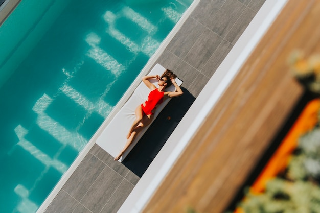 Photo young woman lying by the pool on sunbed at ot summer day