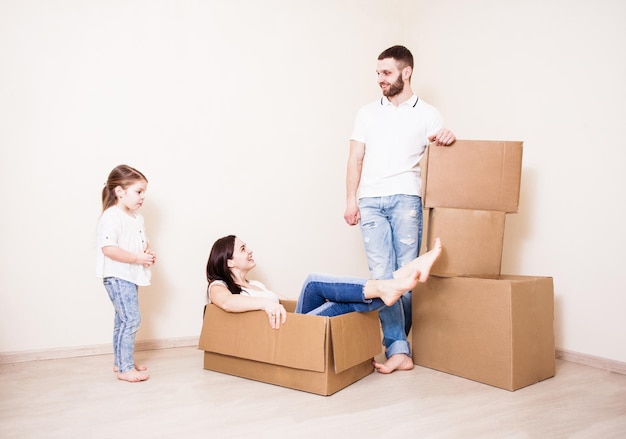 The young woman lying in a cardboard box, and man and little girl are standing next to her