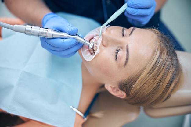 Photo young woman lying in chair while male doctor is putting filling for her