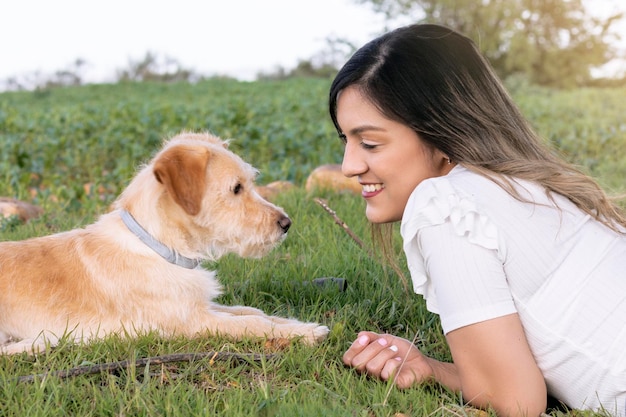 彼女の犬と一緒にフィールドに横たわっている若い女性