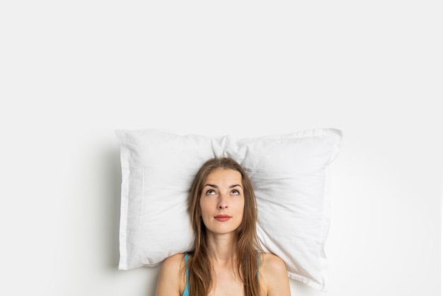 Young woman lying on a pillow looks up Top view flat lay