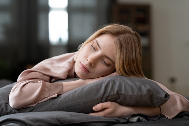 Young woman lying on pillow with eyes closed and sleeping during her relaxing time