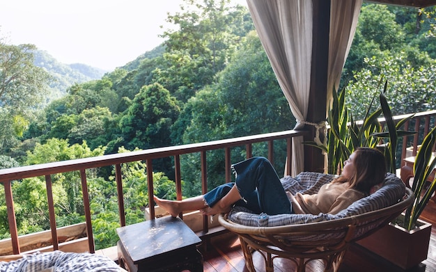 A young woman lying and relaxing on sofa while looking at a beautiful nature view