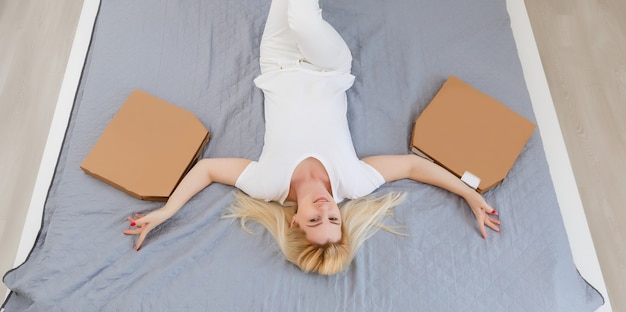 Young woman lying on a sofa and eating pizza