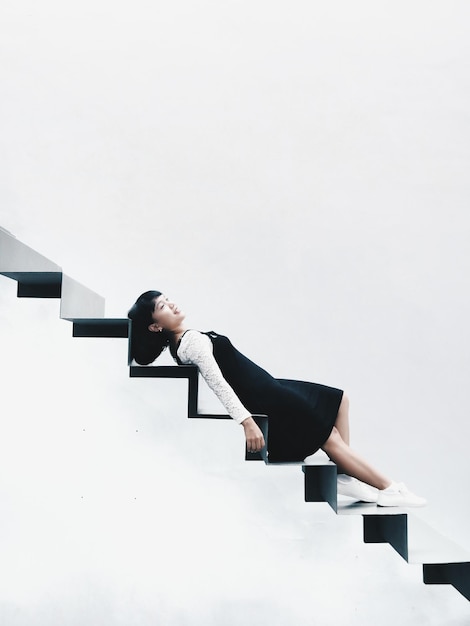 Photo young woman lying on steps against white background