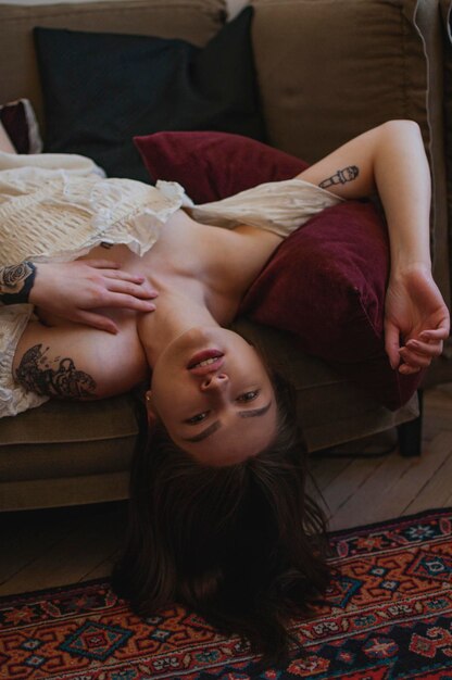 Photo young woman lying upside down on sofa at home