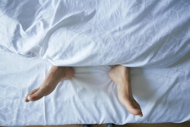 young woman lying with bare feet in bed