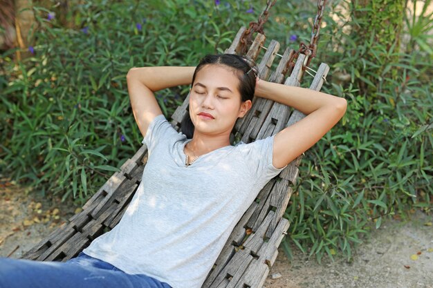 Young woman lying on wood cradle in a garden