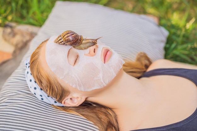 Young woman makes a face mask with snail mucus Snail crawling on a face mask