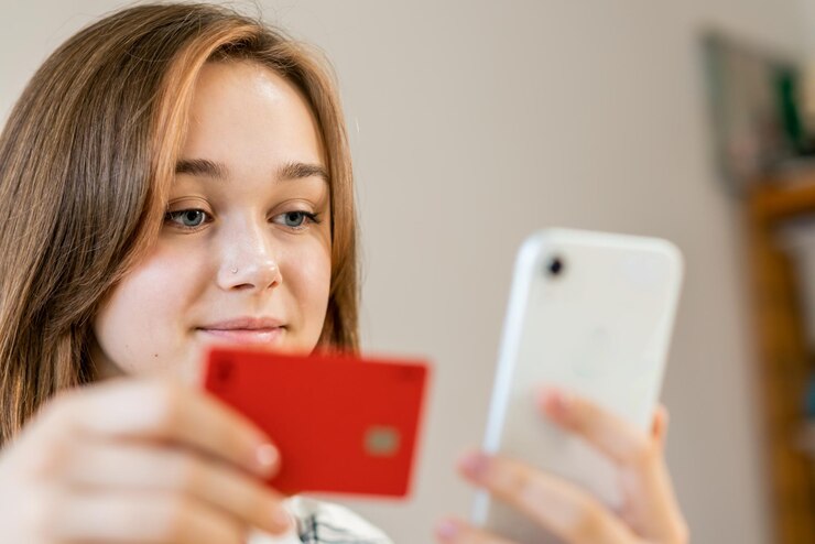 Photo young woman makes purchases online with a credit card using a smartphone at home indoors