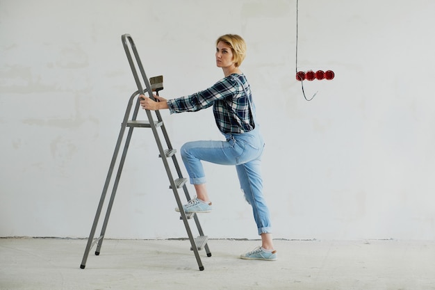 Photo young woman makes repairs in her house