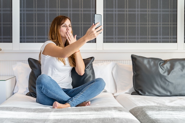 Young woman makes a video call and sends a kiss while talking at home