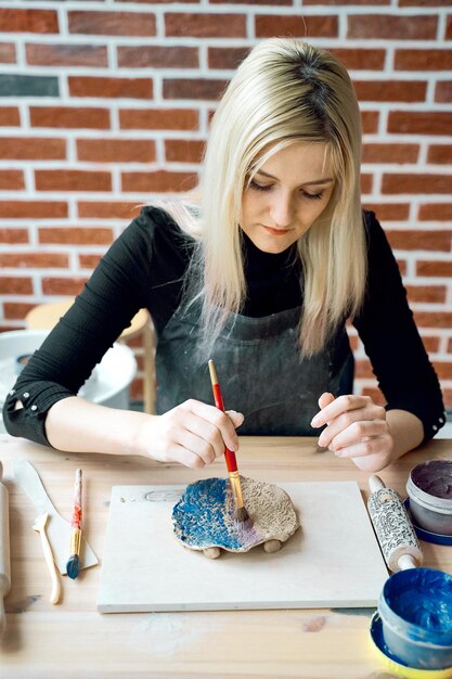 Photo young woman making ceramic plate