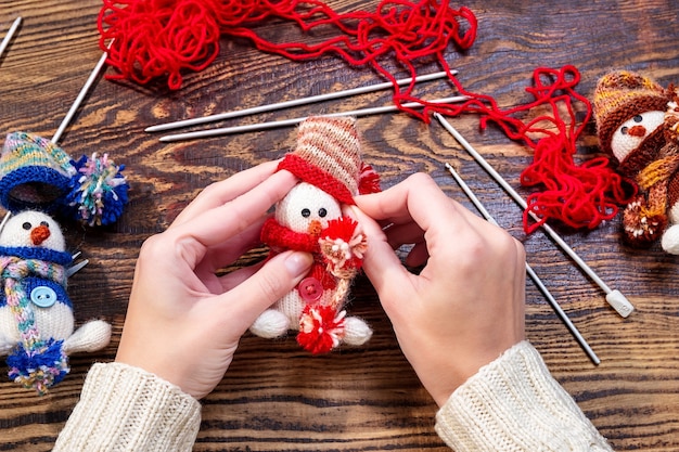 Young woman making Christmas handmade toys on wooden table