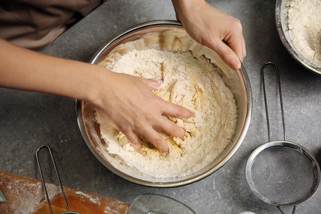 写真 キッチンのクローズアップで生地を作る若い女性