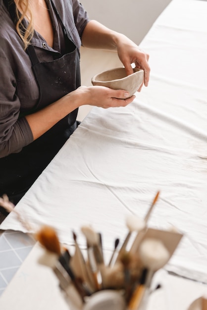 Young woman making earthen pot in pottery workshop