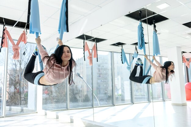 Young woman making exercises of aerial yoga