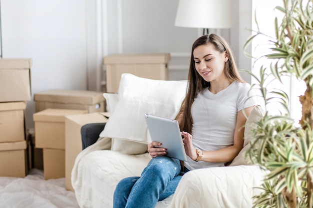 Молодая женщина делает покупки в Интернете для своей новой квартиры. фото с копией пространства