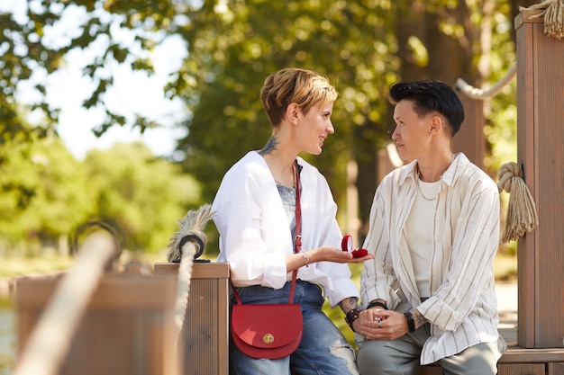 Young woman making proposal to her girlfriend while they sitting in the park