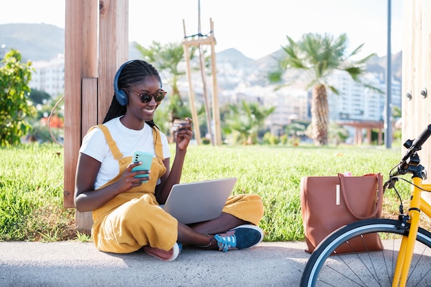 Young woman making a purchase outdoors with her laptop and using a credit card Concept online lifestyle city life